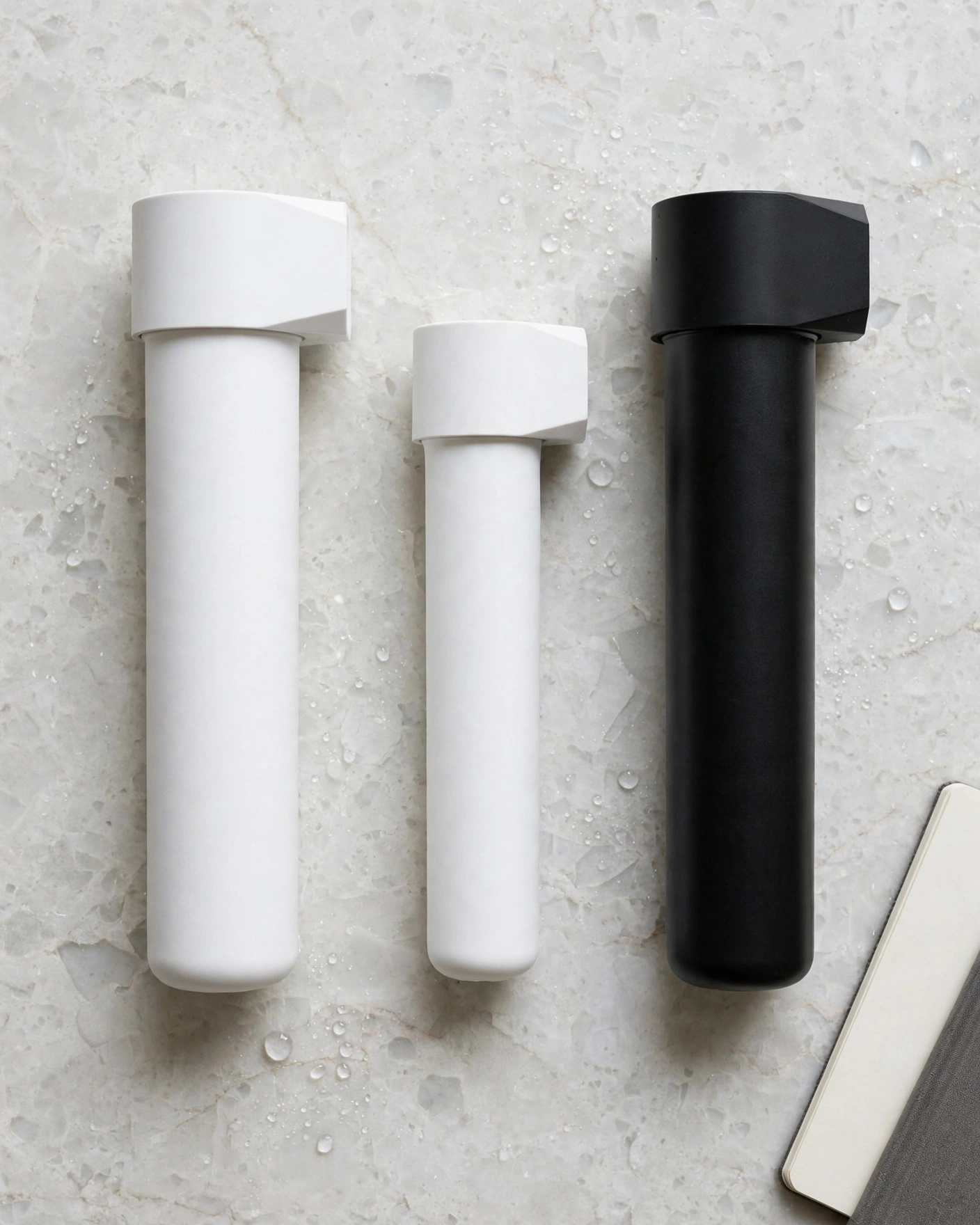 Three unlabeled water filter cartridges in a row, two white and one tall black